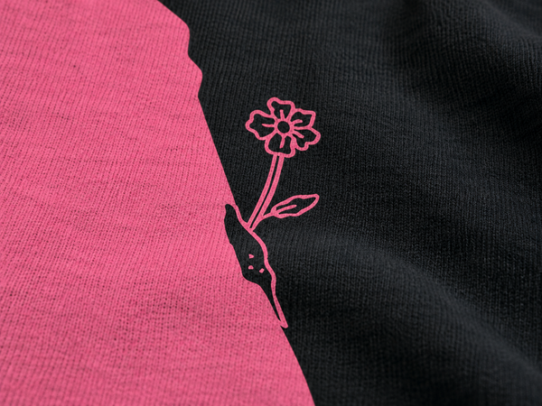 Dettaglio della stampa rosa su felpa girocollo Nero: fiore disegnato accanto a una grande forma rosa