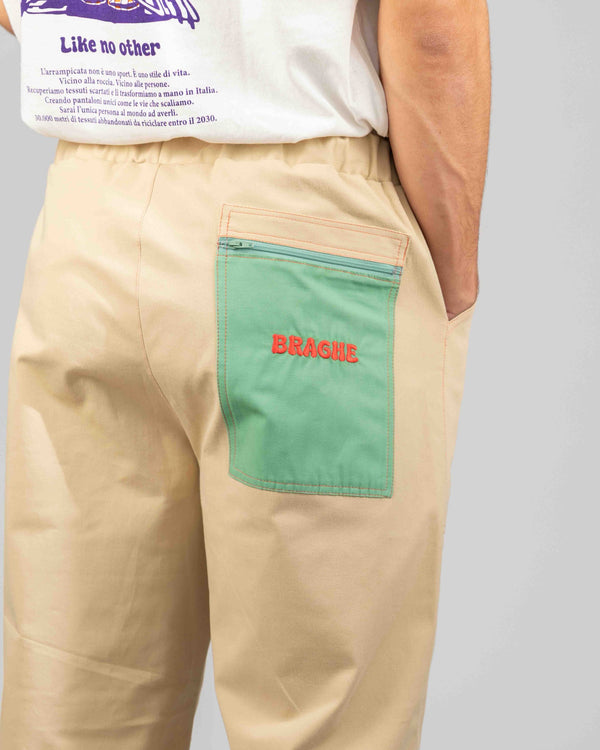 Dettaglio della tasca posteriore verde con zip e logo Braghe rosso dei pantaloni LO SPECCHIO Limited Edition
